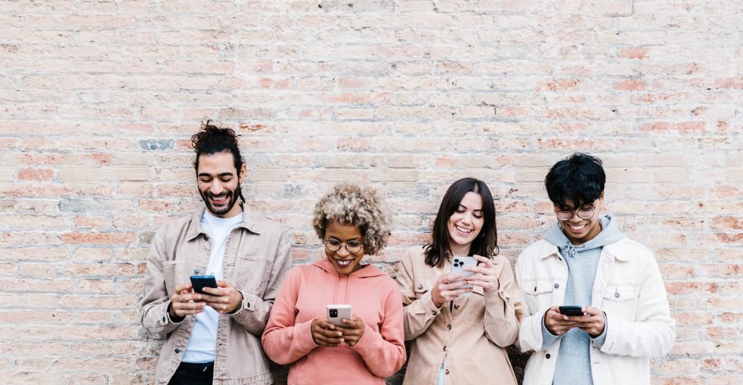 four-multiracial-people-using-mobile-phone-outdoor-2022-03-18-21-00-25-utc.jpg
